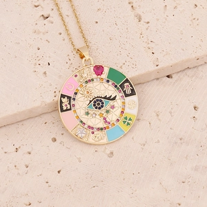 Close-up of a gold evil eye pendant with multi-symbol enamel charms on stone