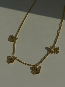Detail of vintage gold butterfly charm necklace with intricate wing textures on links