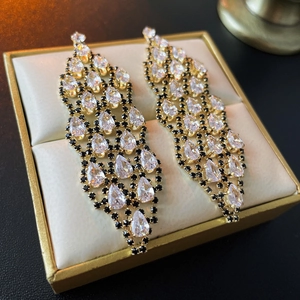 Macro view of gold tassel earrings with zircon and black rhinestones in a jewelry box