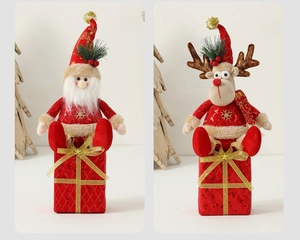Close-up of plush Santa and reindeer Christmas dolls with gold sequins on red fabric
