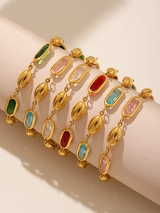 Makroaufnahme des vergoldeten Armbands mit bunten ovalen Edelsteinen auf rosa Display