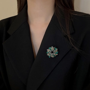 Detailed close-up of a gold floral wreath brooch pinned on a black luxury suit jacket