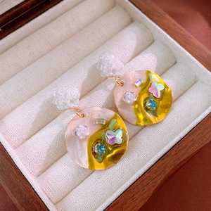 Detail shot of floral and butterfly crystal earrings in a velvet-lined wooden jewelry box