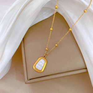 Gold titanium steel necklace with square shell pendant and bead chain on white background