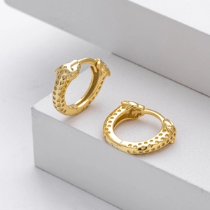 Elegant gold leopard head hoop earrings featuring textured spots on white podium