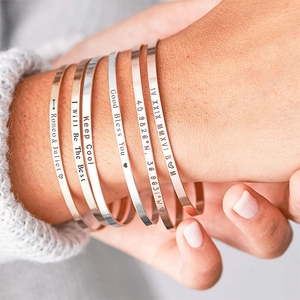 Close-up of polished stainless steel bangles with personalized laser engravings on wrist