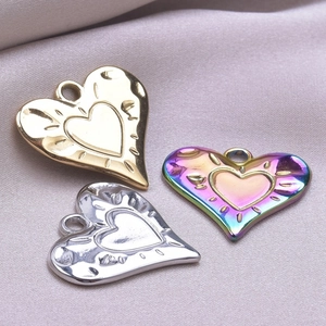 Macro shot of 18k gold and silver heart pendants with ribbed texture on purple silk