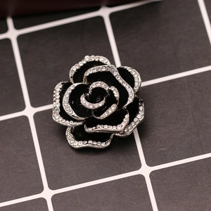 Macro detail of a vintage black camellia brooch with sparkling rhinestones on petal edges