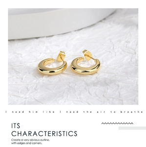 Close-up of chunky C-shape gold earrings with polished metal texture on white background