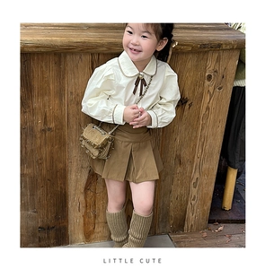 Detail of children's white blouse and brown pleated skirt with matching mini crossbody bag