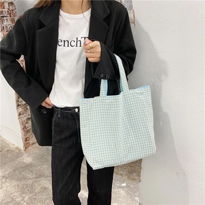 Detalle del bolso tote de lona a cuadros azules llevado por una modelo con estilo casual