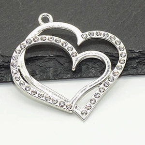 Detail of silver double heart pendant with sparkling crystals on a stone background