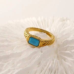 Detailed macro shot of 18k gold vintage ring with engraved texture and blue gemstone