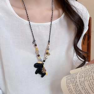 Close-up of black horse pendant necklace with colorful beads and woven rope chain