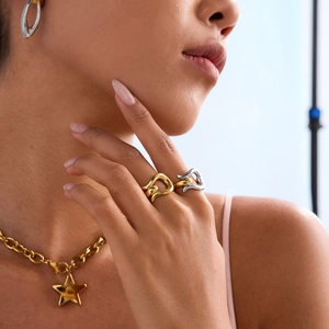 Detail view of gold star pendant necklace and mixed metal streamlined chunky rings