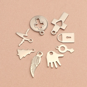 Vue à plat de pendentifs en acier inoxydable avec formes de cœur, croix et arbre