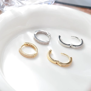 Elegant gold and silver hinged hoop earrings with pavé cubic zirconia on white tray