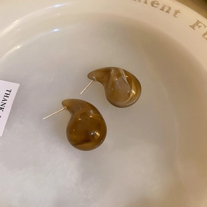 Detailed view of amber resin earrings with marble texture on a white decorative plate
