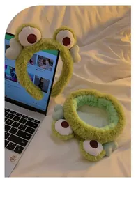 Dettaglio del set di fasce per capelli a rana in peluche verde su un letto