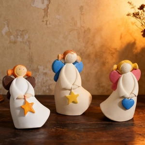 Vue détaillée de trois figurines d'anges minimalistes aux ailes colorées sur bois