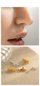 Detail showing golden 'them' letter nose stud with L-shape and screw pin designs