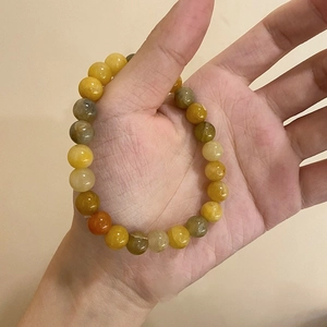 Detail of beaded bracelet with natural yellow, orange and dark green translucent stones