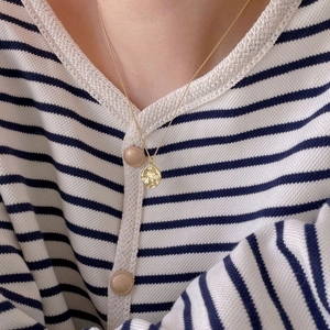 Detail of a 925 silver irregular golden round necklace worn on collarbone with texture