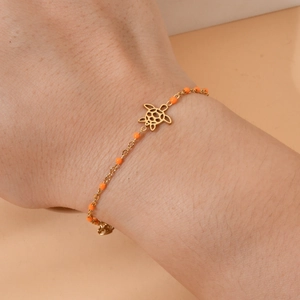 Minimalist gold stainless steel bracelet with orange beads and hollow turtle pendant