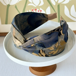 Detail showing the floral fabric texture and brown ribbed ends of a wide knotted headband