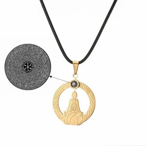 Detail of gold stainless steel lotus pendant with micro-engraved projection stone