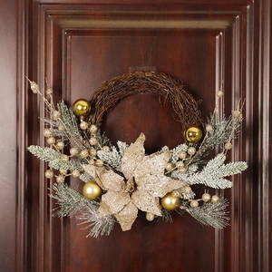 Christmas pine needle wreath with gold ornaments and snow finish on a wooden door