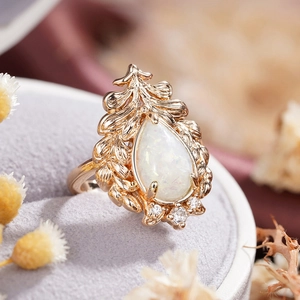 Macro view of Baroque gold ring with pear-shaped opal and white zircon detailing