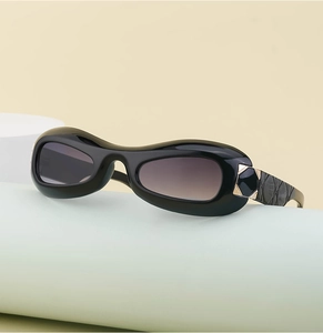 Detail of black oval sunglasses featuring quilted texture and golden metal accents