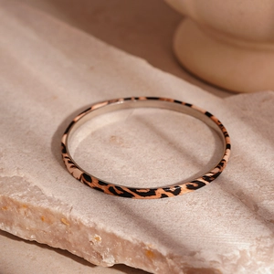 Close-up of leopard print bracelet on a natural stone surface with silver inner band