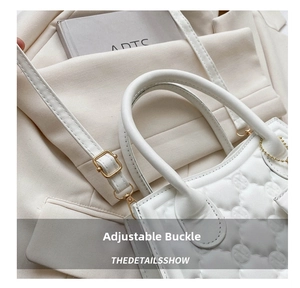 Close-up of white quilted handbag featuring an adjustable metal buckle on the shoulder strap