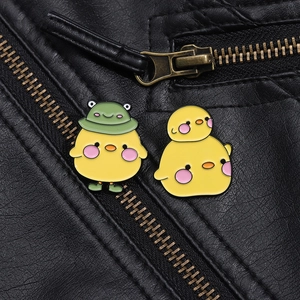 Detailed close-up of cute yellow chick enamel pins on a black leather jacket texture