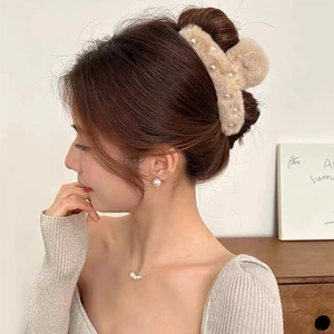 Detail view of light camel plush hair claw clip with pearl accents on model hair
