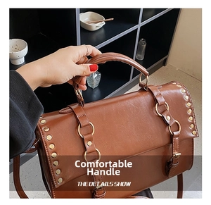 Detail of brown leather handbag featuring gold buckles, rivets, and a sturdy top handle