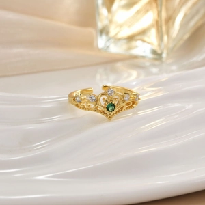 Detailed macro of a golden crown ring with a green gemstone on a ceramic tray