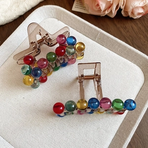 Detailed shot of star and bar acrylic hair claws with vibrant translucent beads