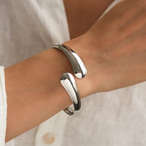 Close-up of polished silver cuff bangle with sleek water-drop ends on model wrist