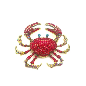 Golden crab brooch with red and rainbow rhinestones on a clean white background
