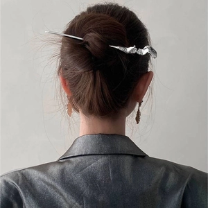 Close-up of a silver lava-textured metal hair stick styled in a sleek Chinese bun
