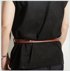 Detailed view of a brown leather belt with metal snap fasteners worn on black clothing