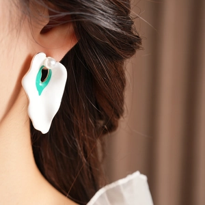 Close-up of vintage enamel petal earring with green center and pearl on model