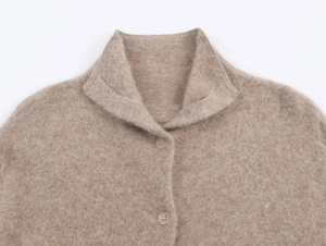 Dettaglio di un cardigan in maglia color avena con colletto a risvolto e bottoni abbinati