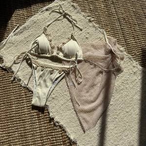 Detail of ribbed cream bikini with starfish charms and matching purple mesh skirt
