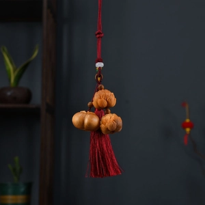 Detail of wooden lotus and pumpkin pendant with red tassels for car or bag decoration