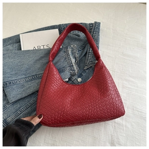 Close-up of red woven leather shoulder bag detailing fine craft on denim background