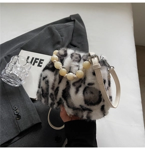 Detail of leopard print faux fur bucket bag featuring a yellow beaded handle and slim strap